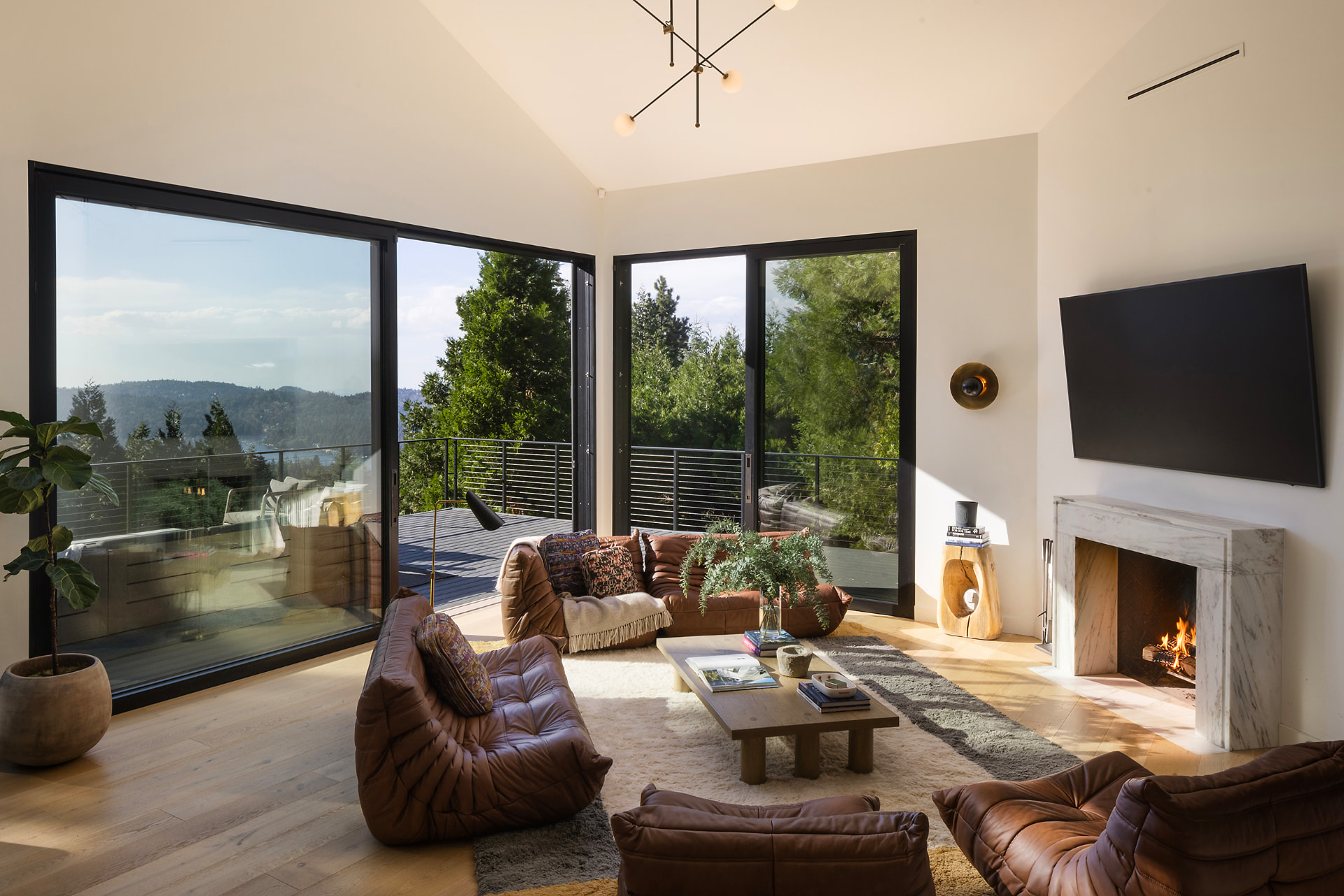 Warmly lit living room with a glowing fireplace and lake views through corner windows