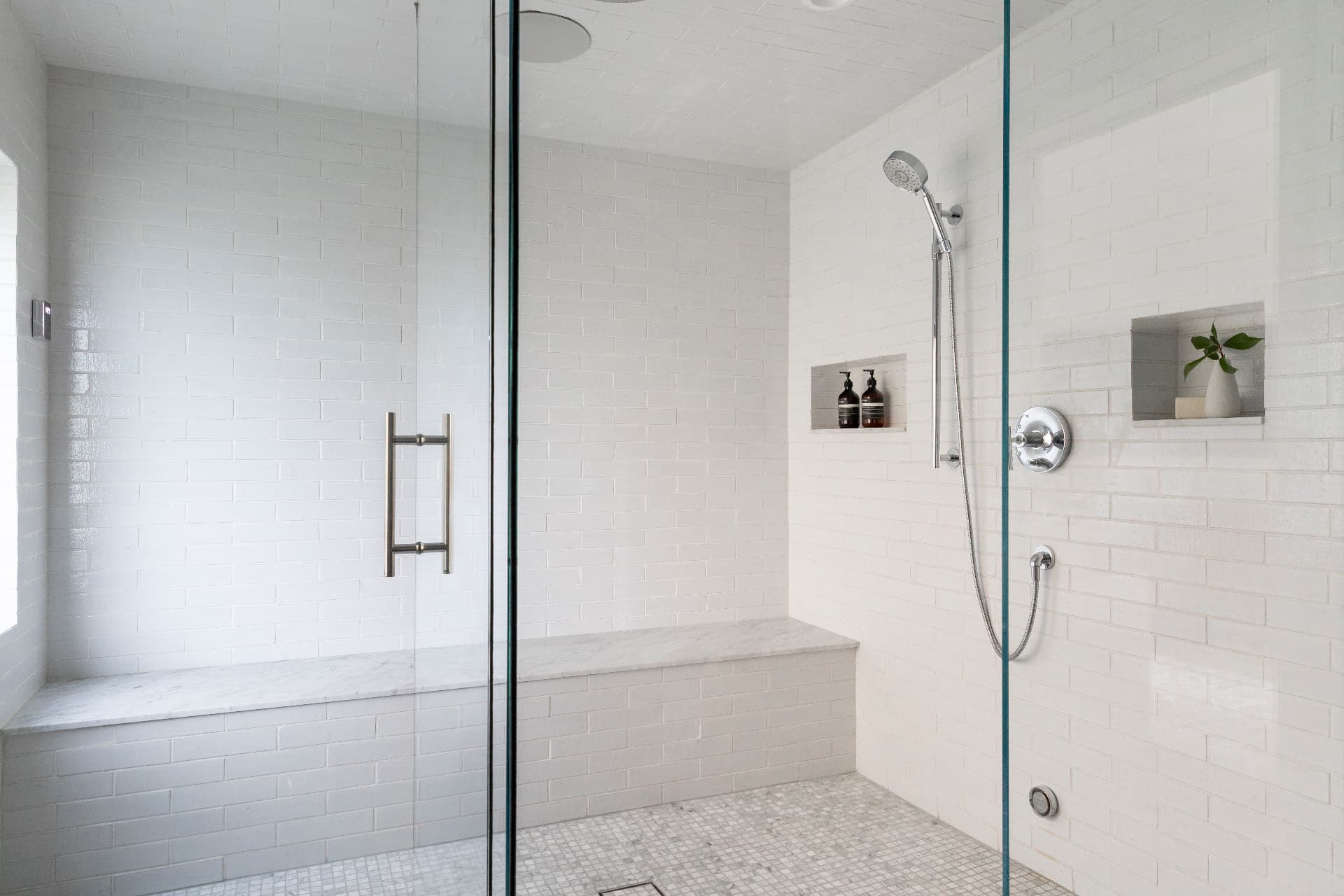 White-tiled steam shower with a built-in bench and glass enclosure